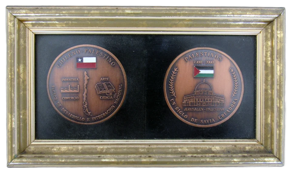 Marco dorado con dos medallas cobrizas sobre fondo negro