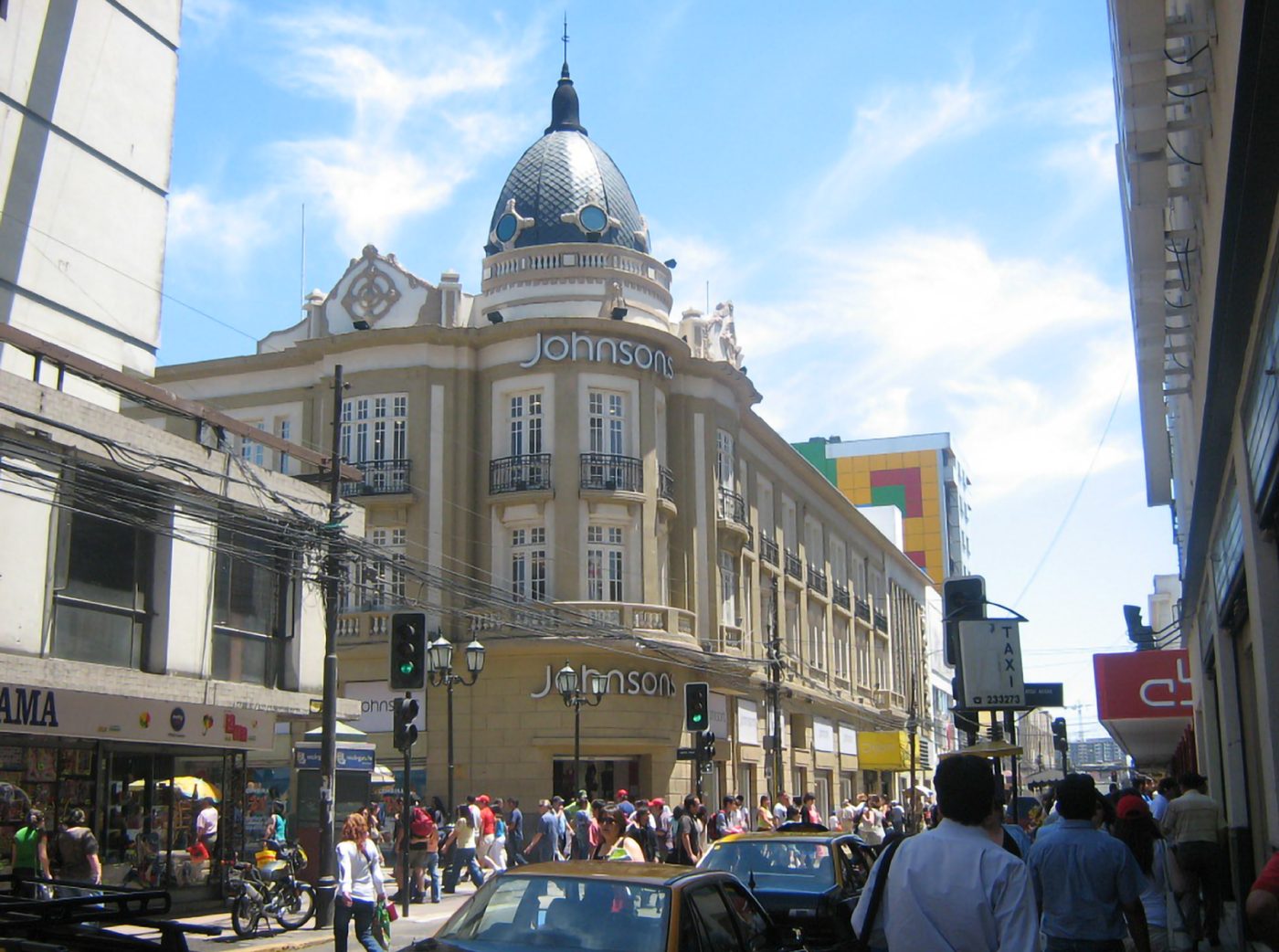 Edificio de esquina con cúpula en una calle comercial concurrida