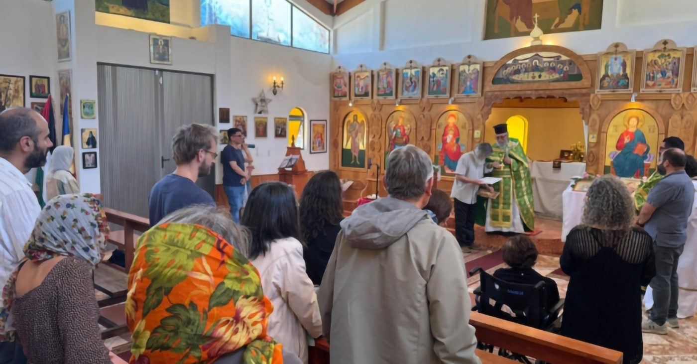 Fieles en una iglesia frente a un iconostasio con íconos dorados