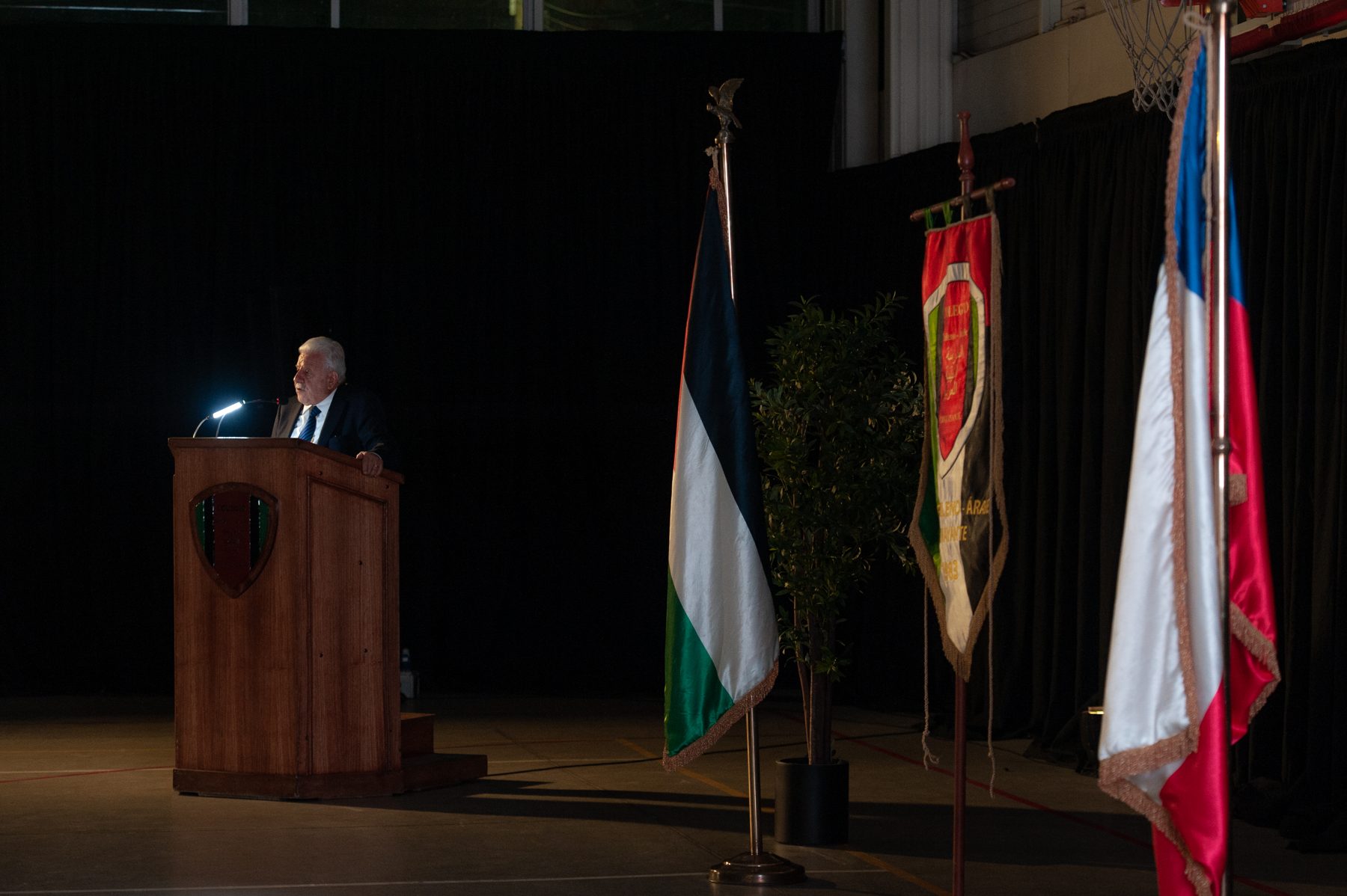 El podio en el escenario, entre la bandera de Palestina y la de Chile