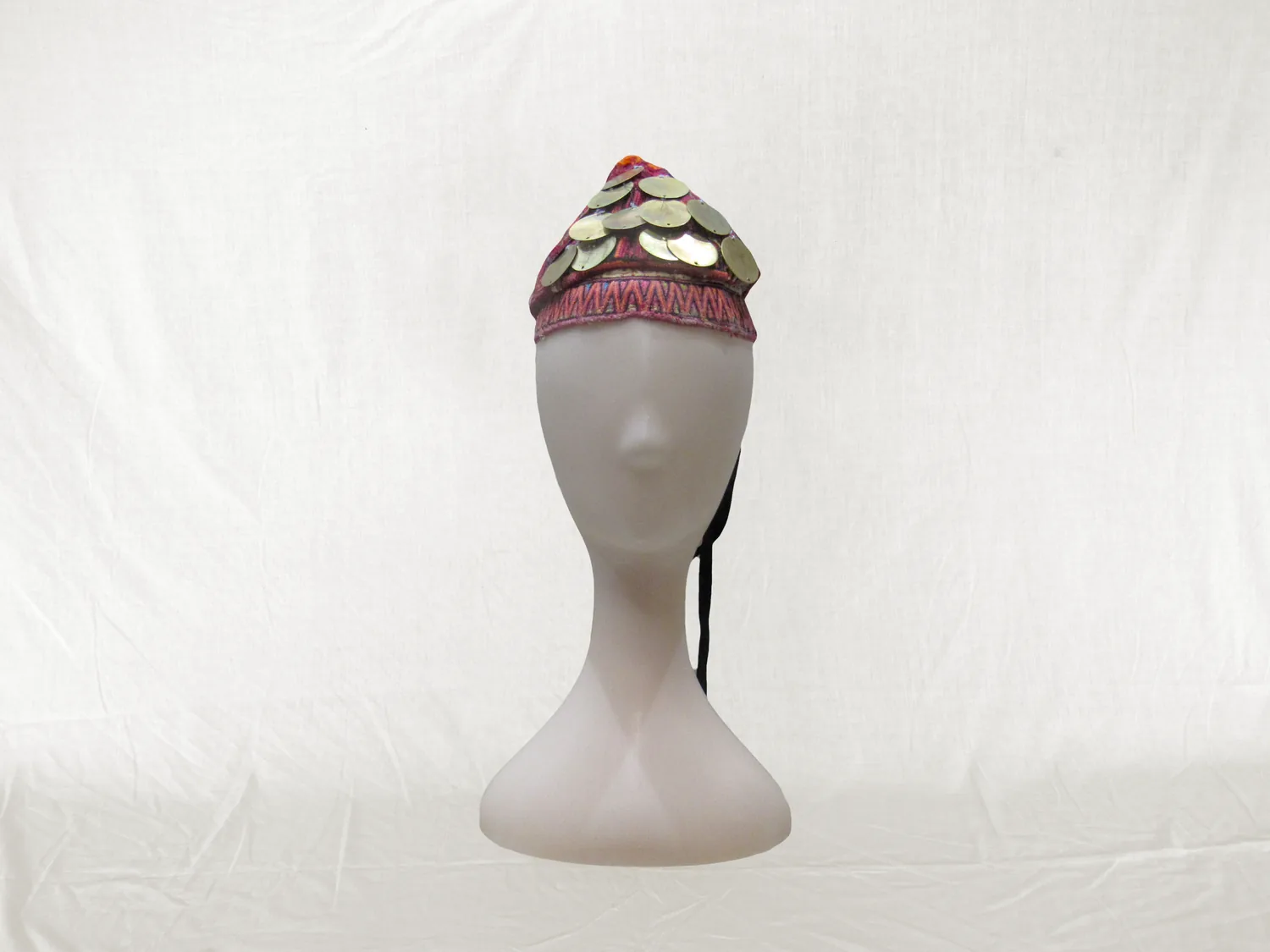 Gorro bordado con discos dorados sobre una cabeza de maniquí