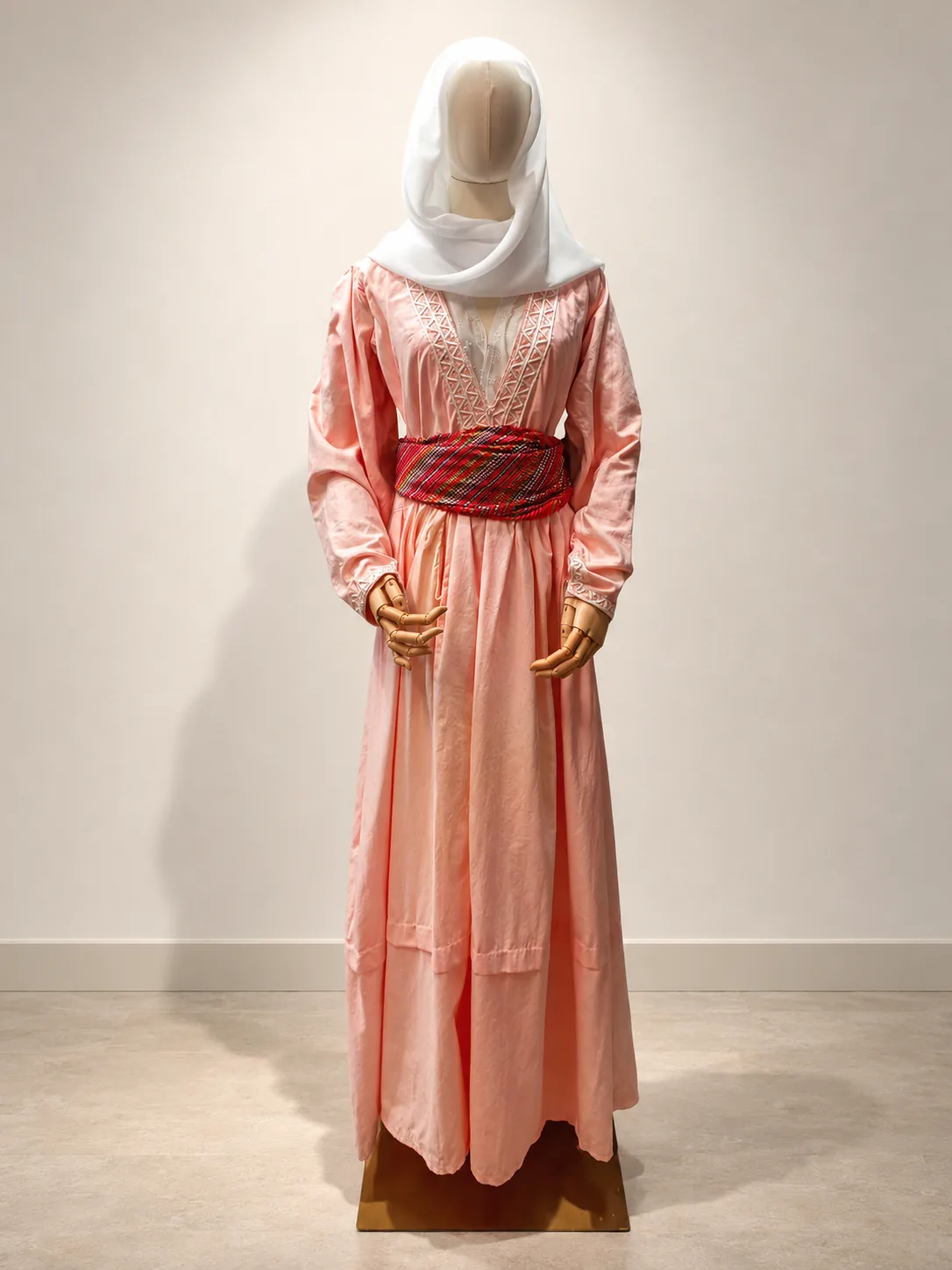 Vestido rosa claro con cinturón rojo y velo blanco, sobre maniquí